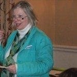 A mum in a green jacket speaking to a group of people about work-life balance for women returners.