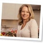 A woman achieving work-life balance in her career while standing in front of a kitchen full of fruits and vegetables.