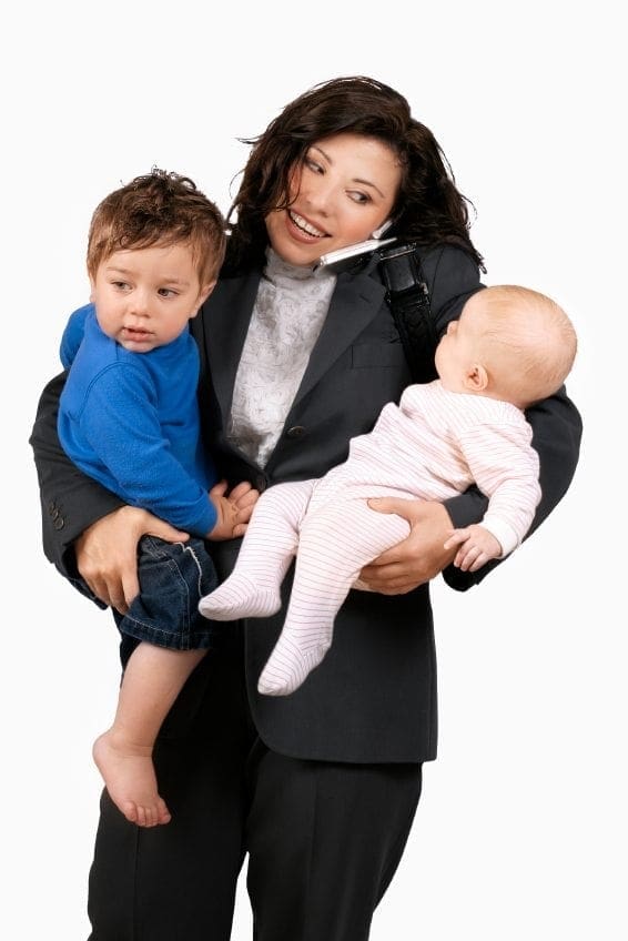 A working woman in a business suit, demonstrating work-life balance as she holds two small children.