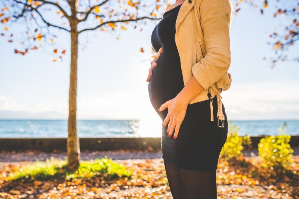 A pregnant woman standing in front of a tree, symbolizing the journey of motherhood for women returners.