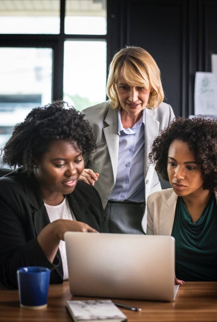 A group of working women looking at a laptop, balancing work and family life.