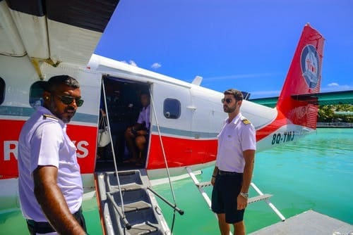 Two men, working, standing on the steps of a small plane.