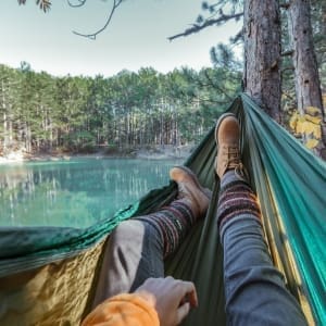 A serene mother finding solace in a hammock by a peaceful lakeside.