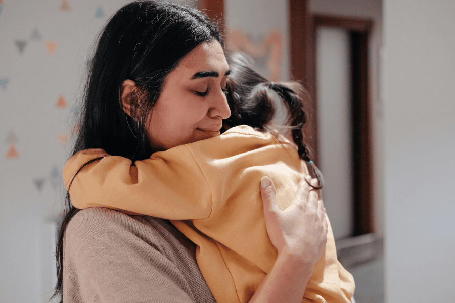 A mother embracing a child in a yellow hoodie, capturing the complex weight of parental guilt.