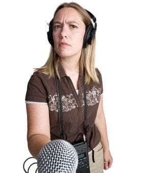 A woman with headphones working on her career, holding a microphone.