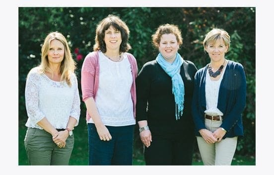 Four women standing next to each other, showcasing their strong career and job roles while posing in front of a tree. Four women standing next to each other, showcasing their strong career and job roles while posing in front of a tree.
