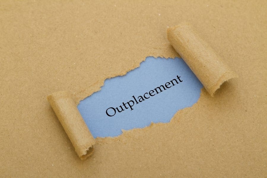 A piece of paper with the word outplacement written on it, specifically designed for women returners seeking work-life balance after being a mum.