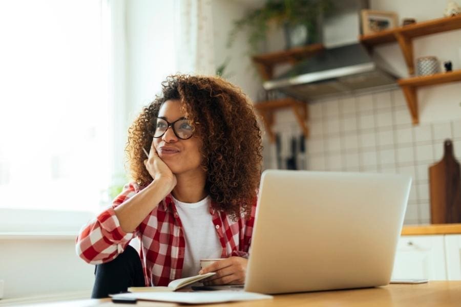 A woman working at a table with a laptop in front of her.