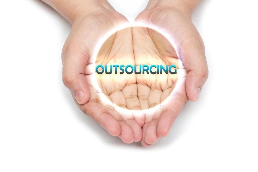 A pair of hands holding the word outsourcing on a white background, highlighting working women.