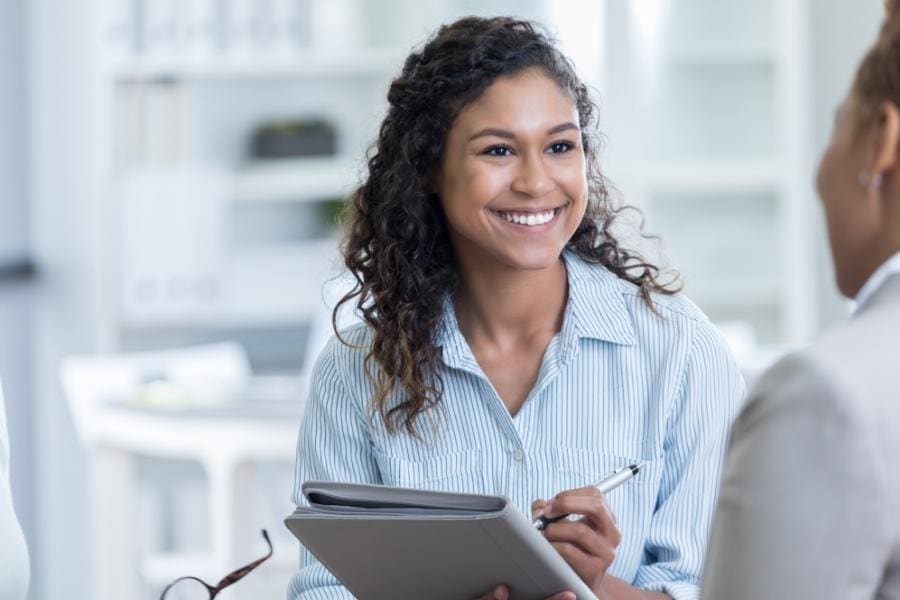 Two women discussing career and work-life balance in an office.