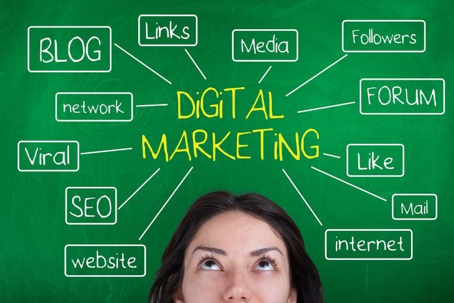 A woman studying a green chalkboard displaying tips for getting into digital marketing.